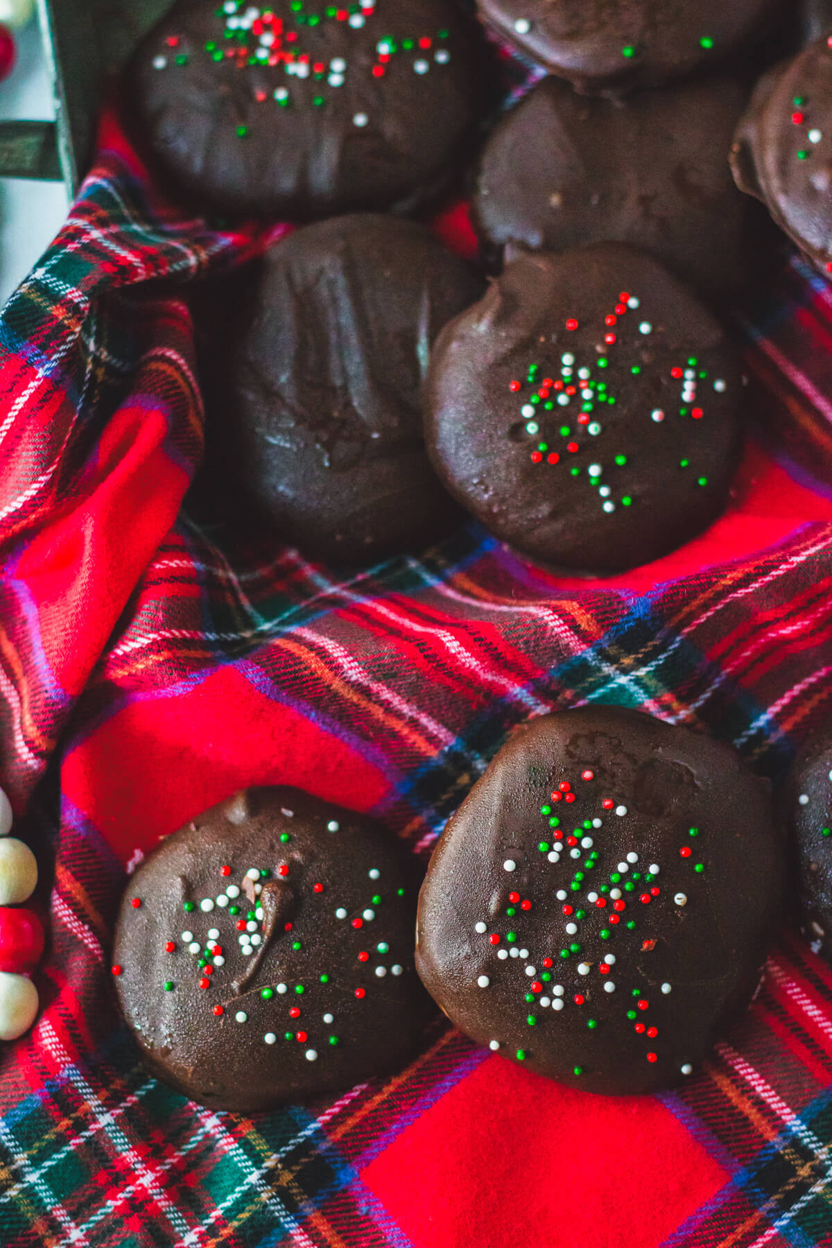 A group of dark chocolate coated peppermint patty candies on a plaid tablecloth.