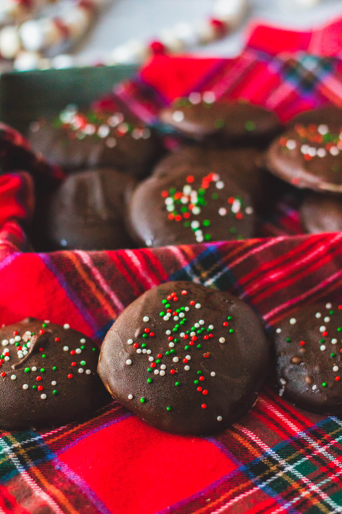 A group of dark chocolate coated peppermint patty candies on a plaid tablecloth.