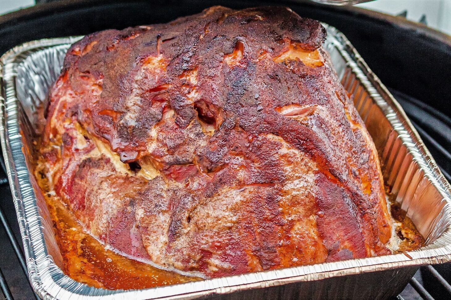 A glistening glazed double smoked ham in a smoker.