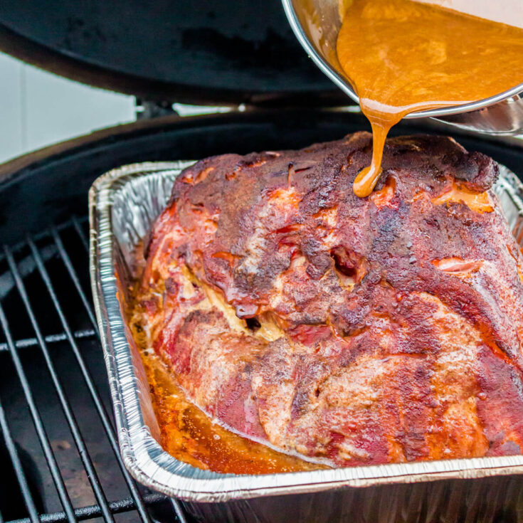 Honey Mustard Glaze being poured on a Double Smoked Ham in a smoker.