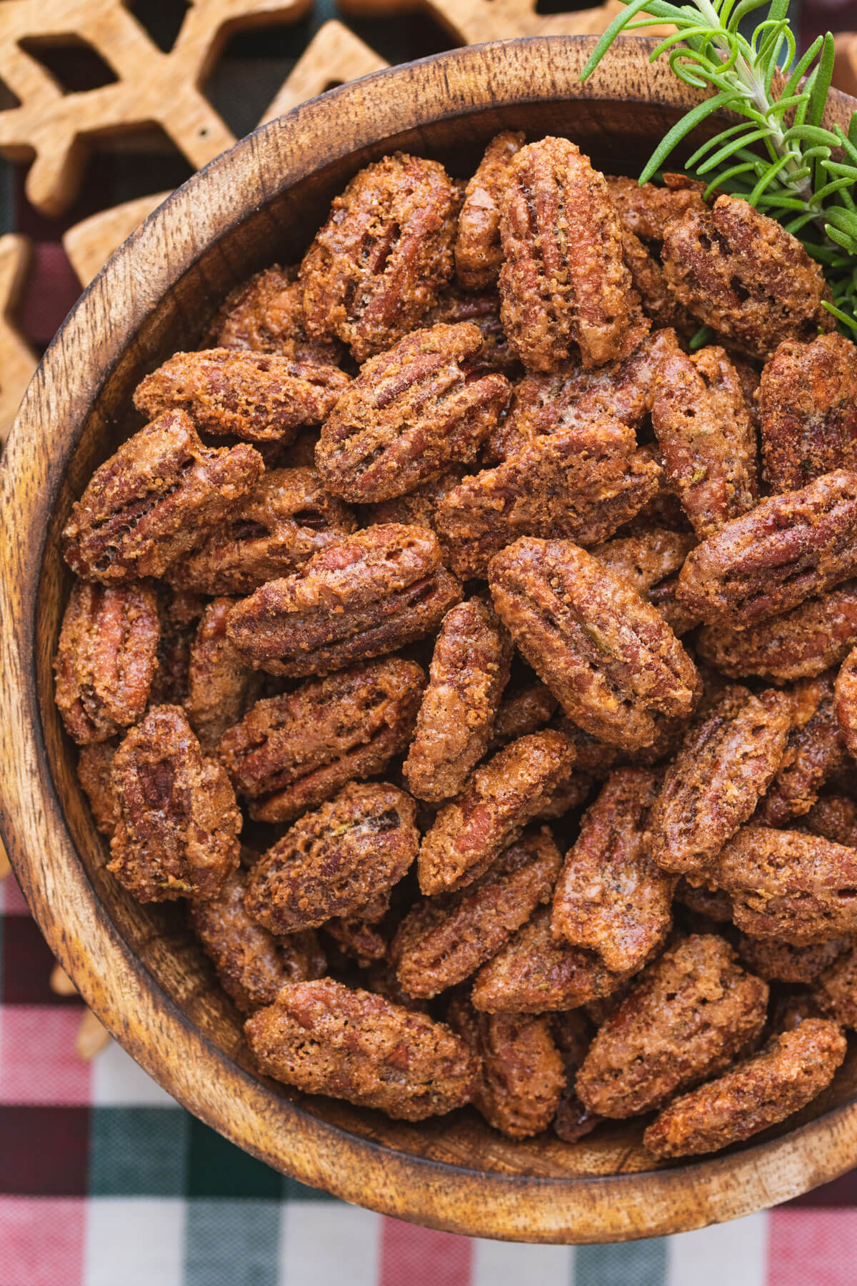Close up of a wooden bowl filled with candied pecans.