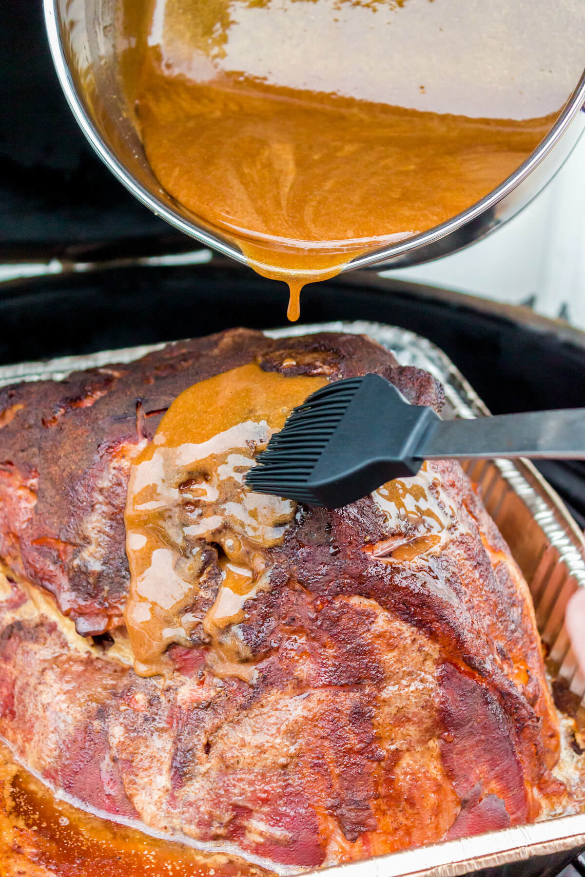 Honey Mustard Glaze being poured on a Double Smoked Ham in a smoker.