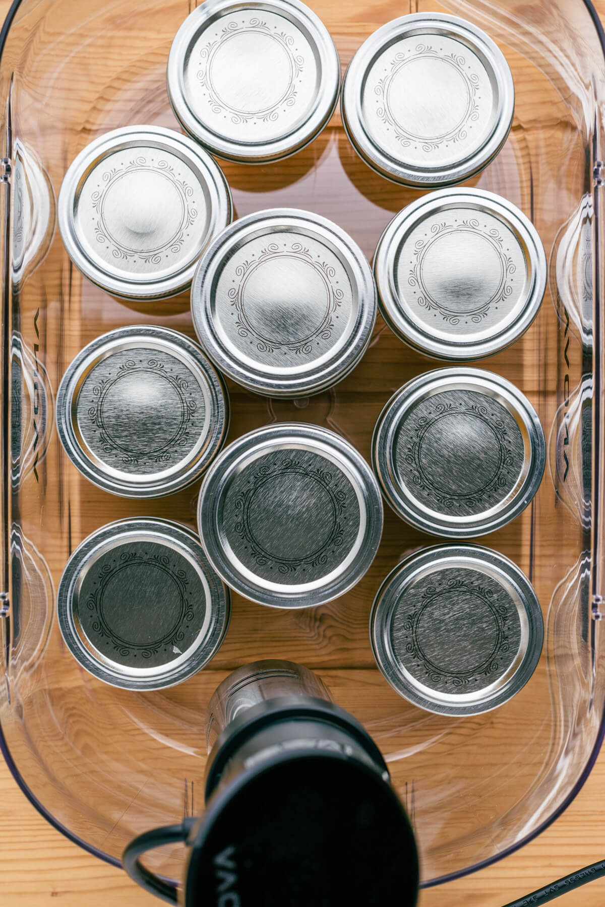 Jars arranged in a sous vide container on a wooden table.