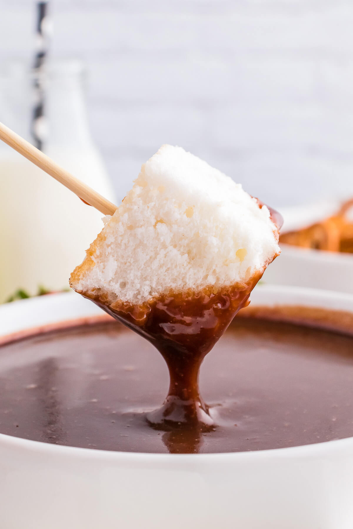 A cube of angel food cake dripping over a chocolate fondue.