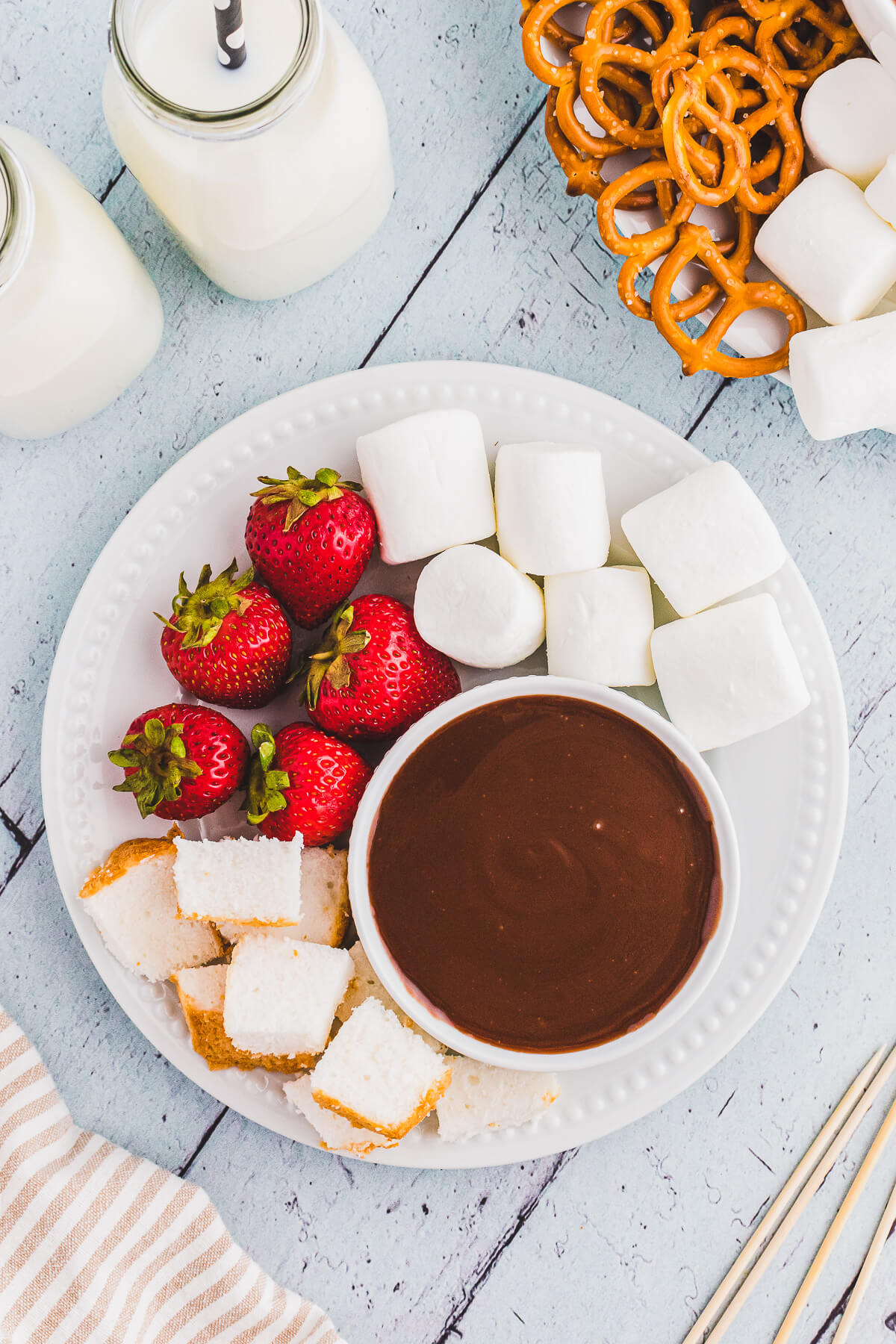 A dessert platter featuring a bowl of melted chocolate fondue surrounded by items for dipping.
