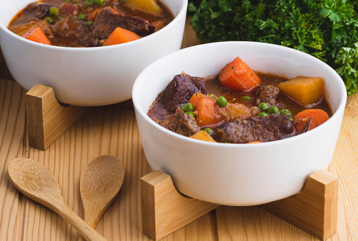 Two white bowls filled with Instant Pot Beef Stew featuring large chunks of tender vegetables and melt in your mouth beef.