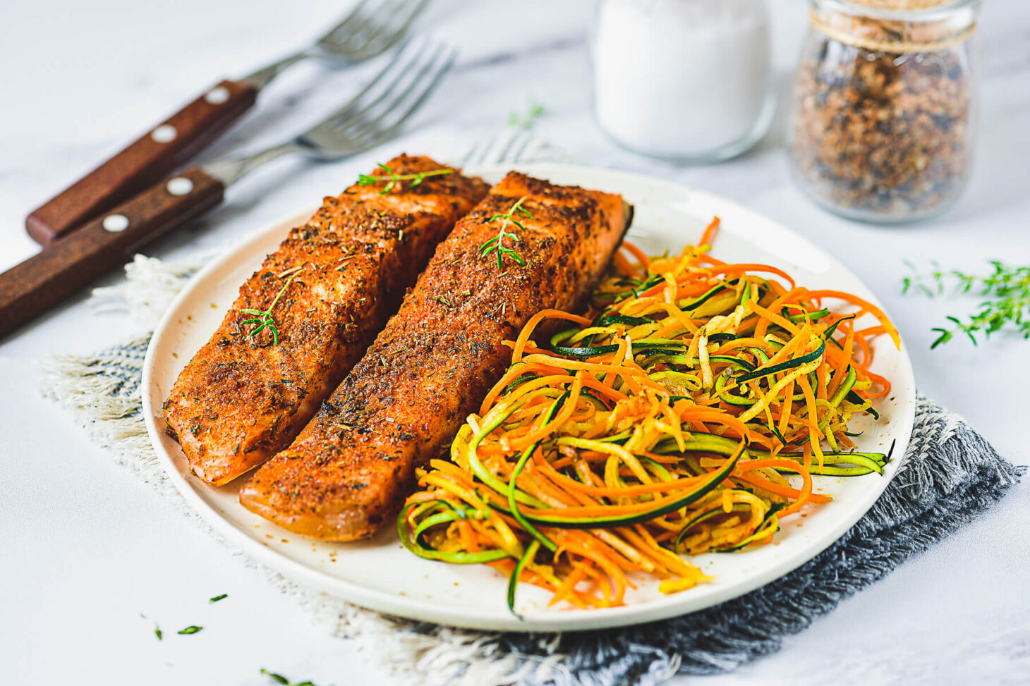 Cover photo for air fryer salmon recipe featuring two cooked spiced salmon fillets on a plate beside spiralized vegetables.