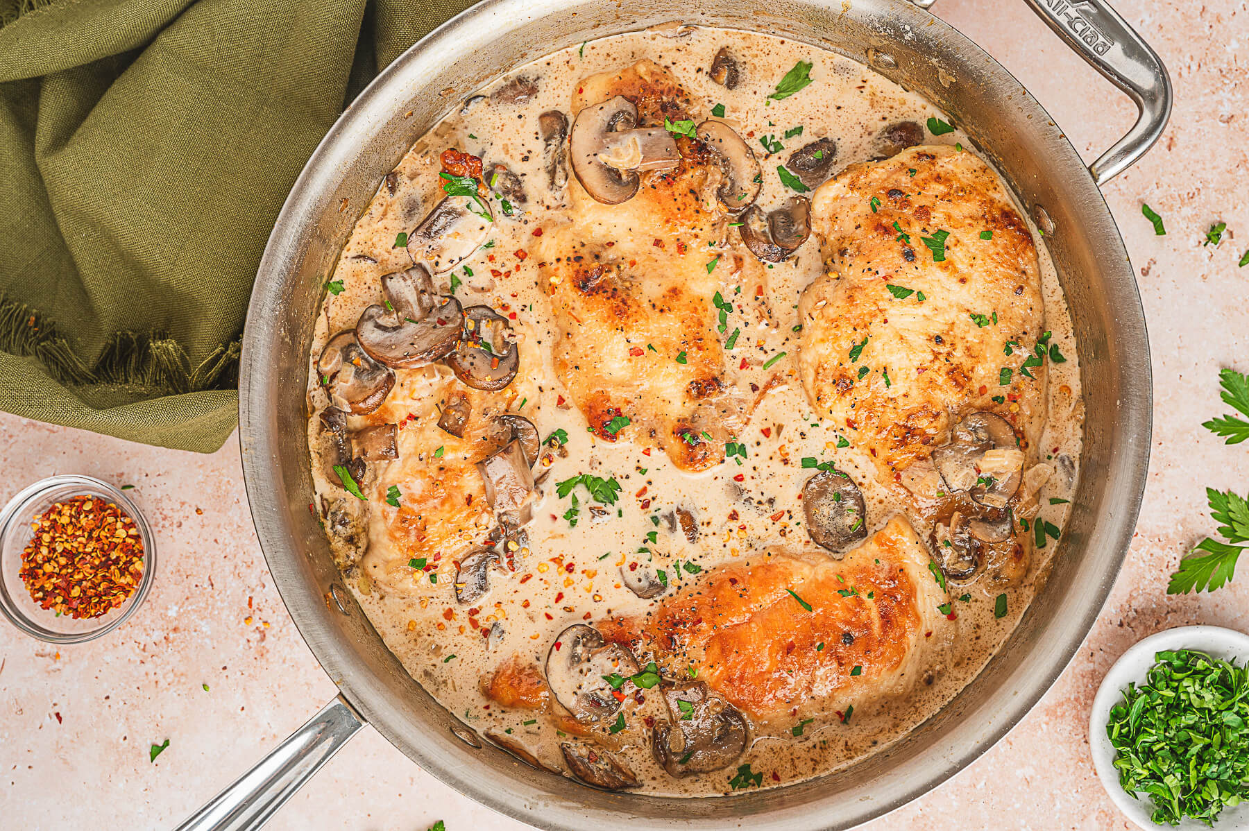 Cooked chicken breasts and mushrooms swimming in a saucepan of creamy marsala sauce.