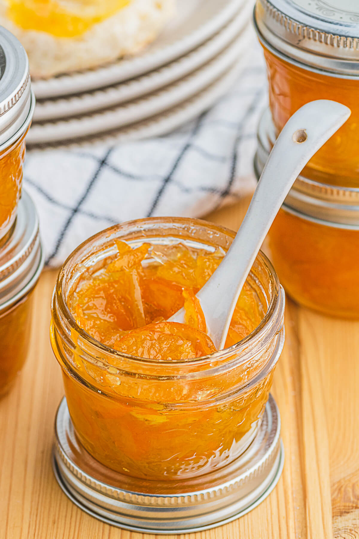 A small jar of bright Kumquat Marmalade with a tiny pottery spoon. 