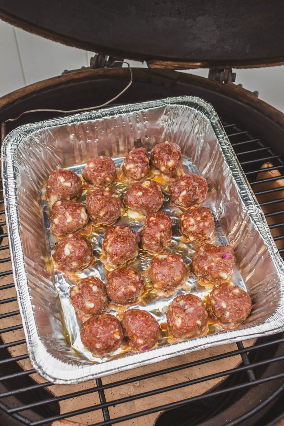 A tray of smoked meatballs on a grill. 