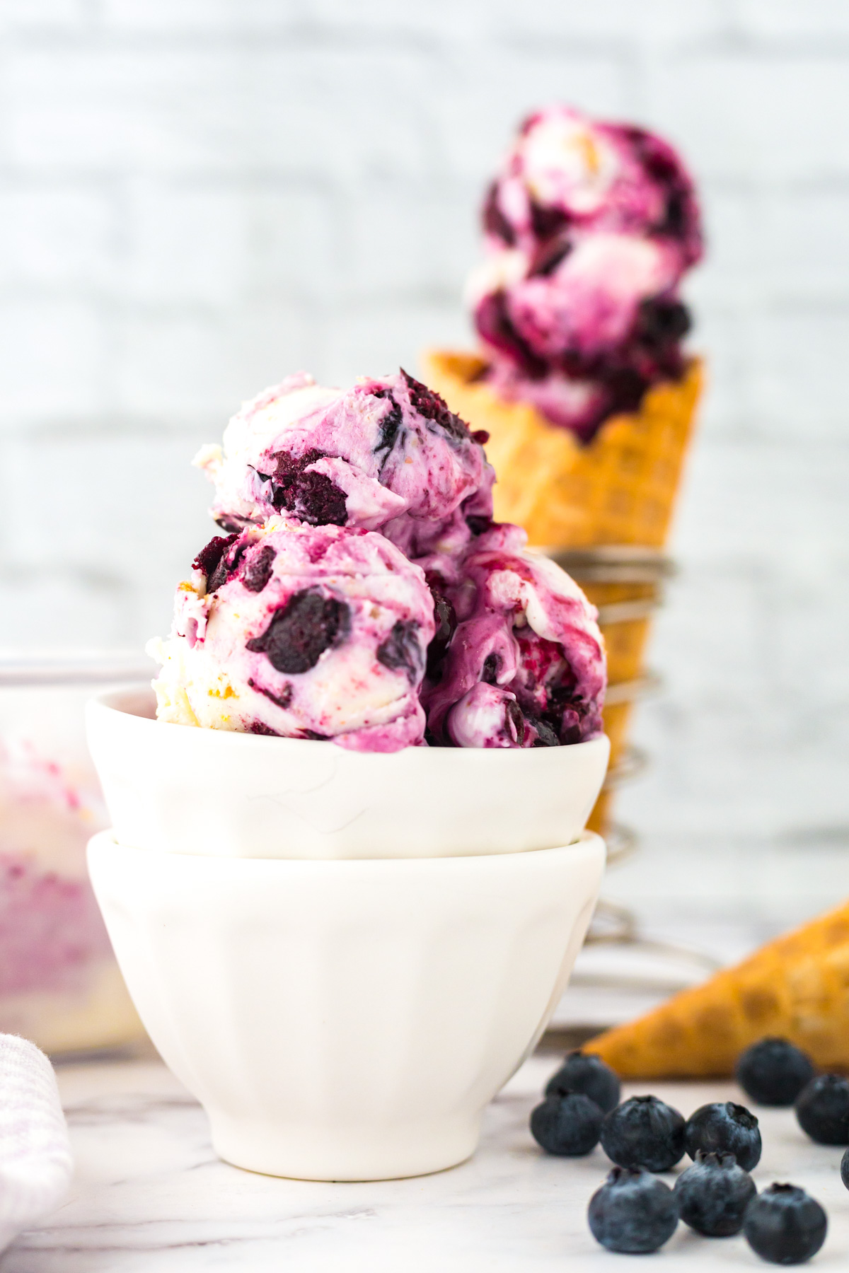 A stack of white bowls filled with creamy Blueberry Cheesecake Ice Cream.
