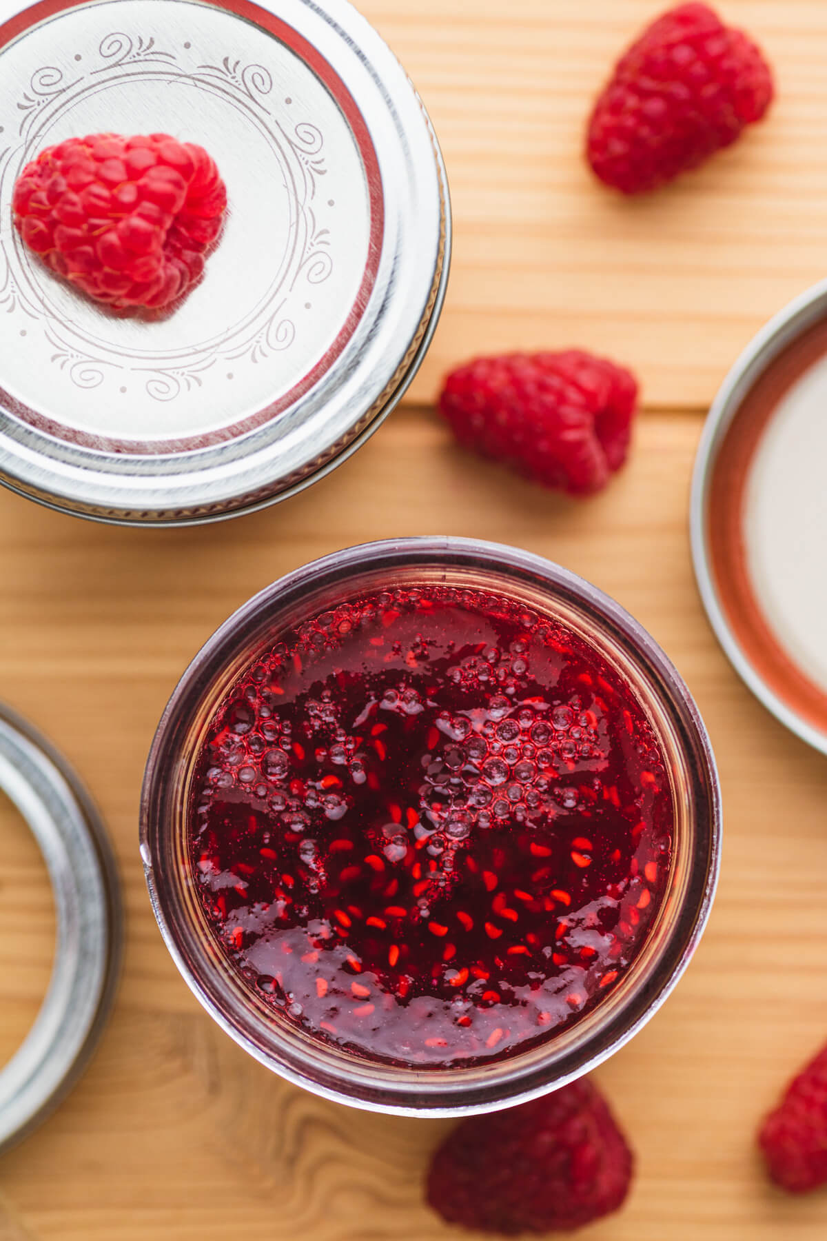 An overhead photo of an open jar of raspberry jam.