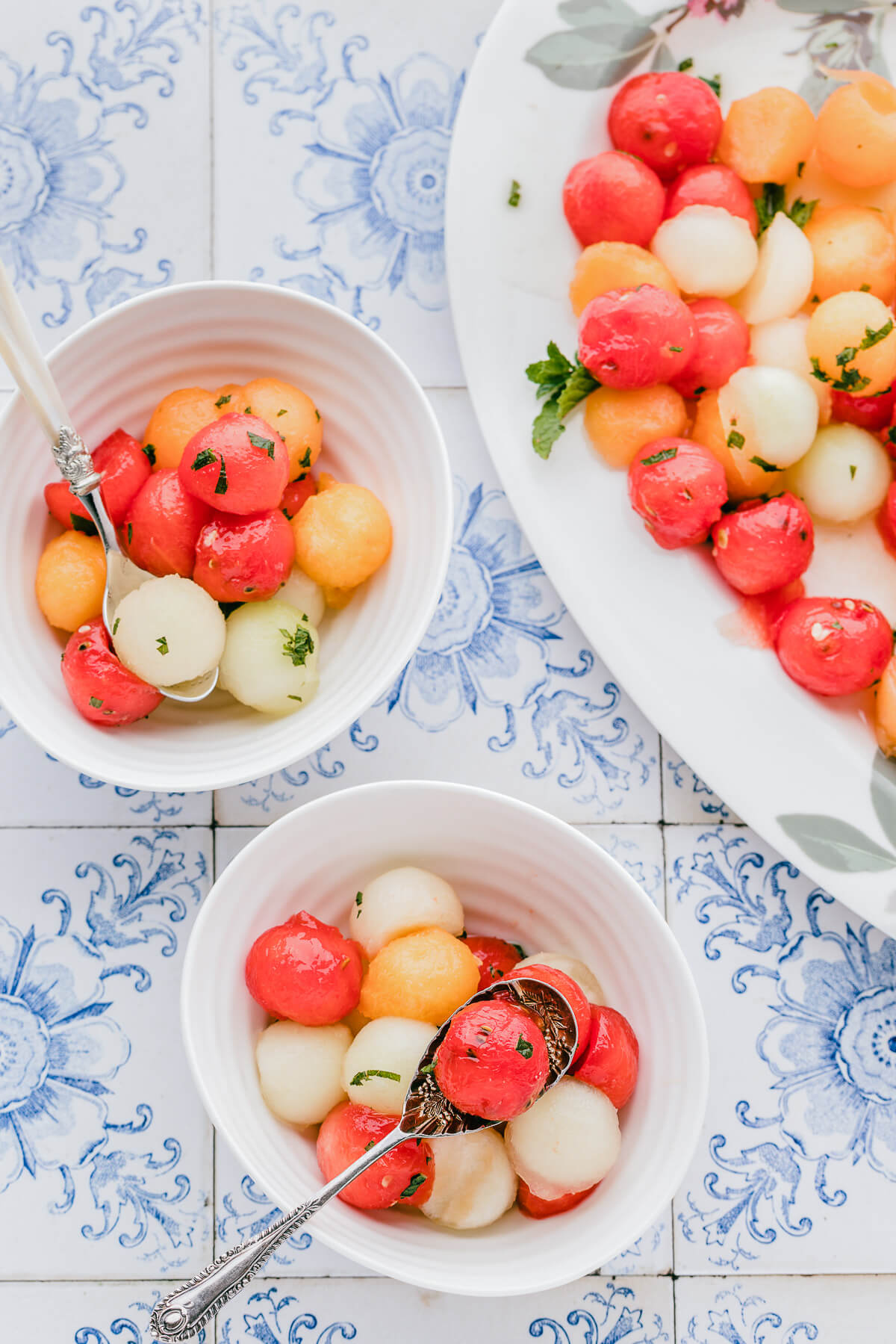 Serving bowls filled with multicoloured melon salad garnished with fresh mint.
