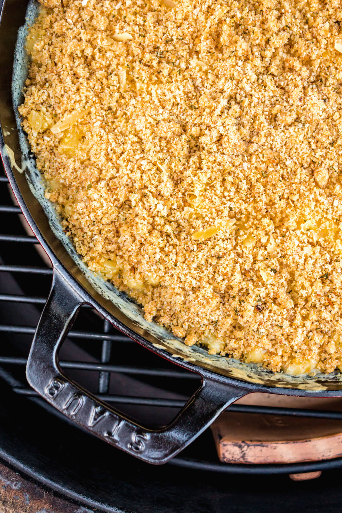 A black cast iron pan full of creamy Smoked Mac and Cheese topped with toasted golden bread crumbs in a smoker.