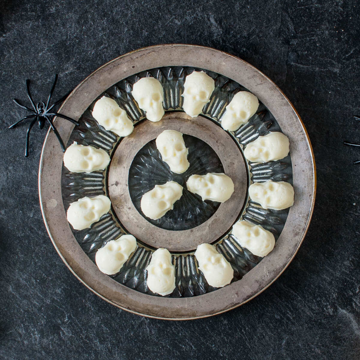 A round silver platter of mozzarella shaped into little skulls.
