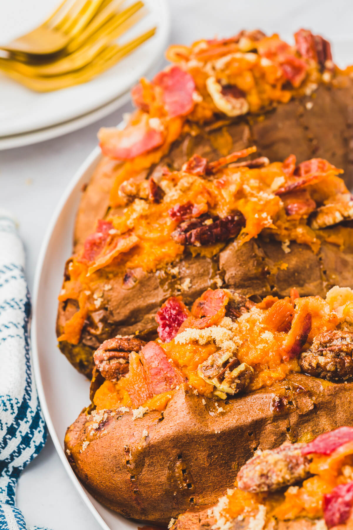 Four Twice Baked Sweet Potatoes topped with crispy bacon and pecans on a white plate.