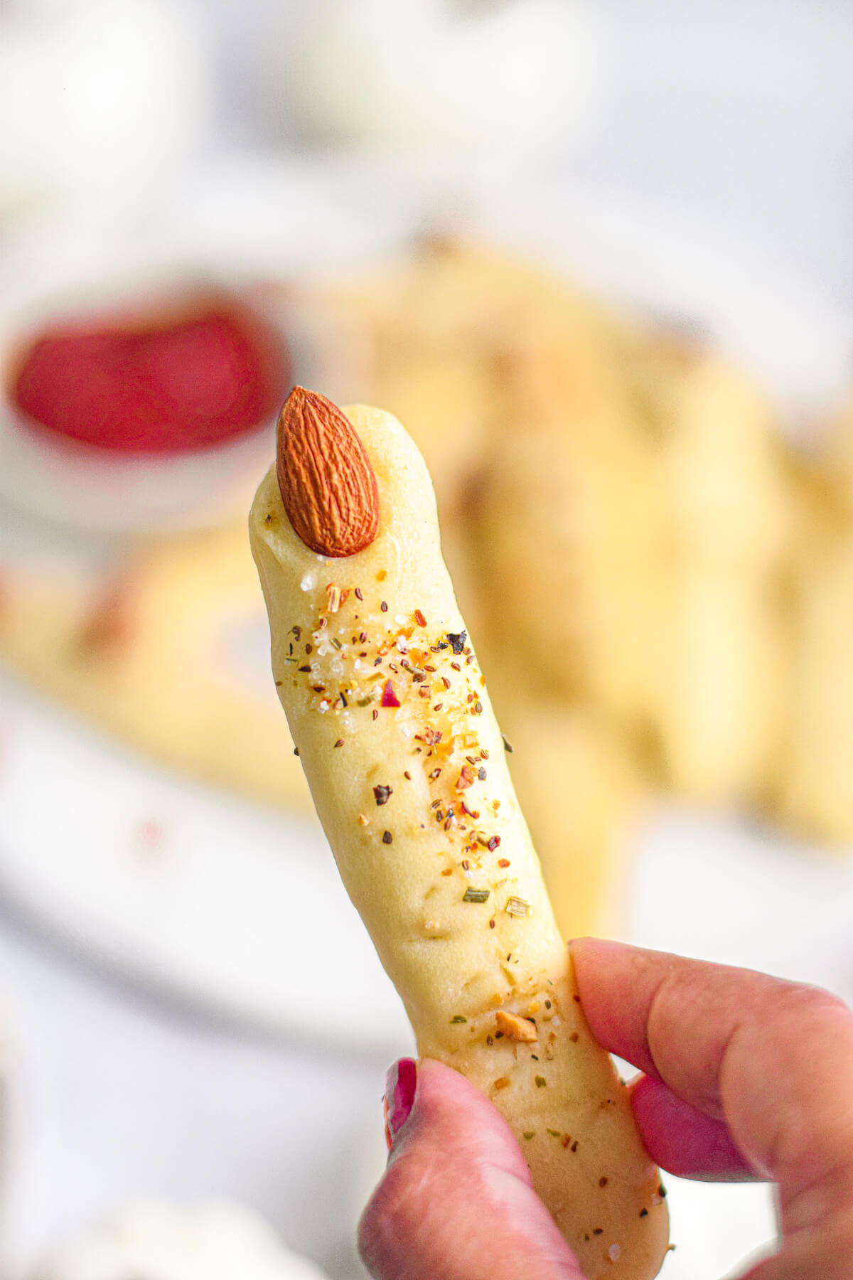 A hand holds an Italian breadstick shaped like a witch's finger.