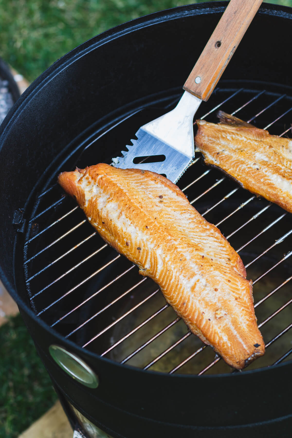 Two smoked trout fillets on a smoker grill.