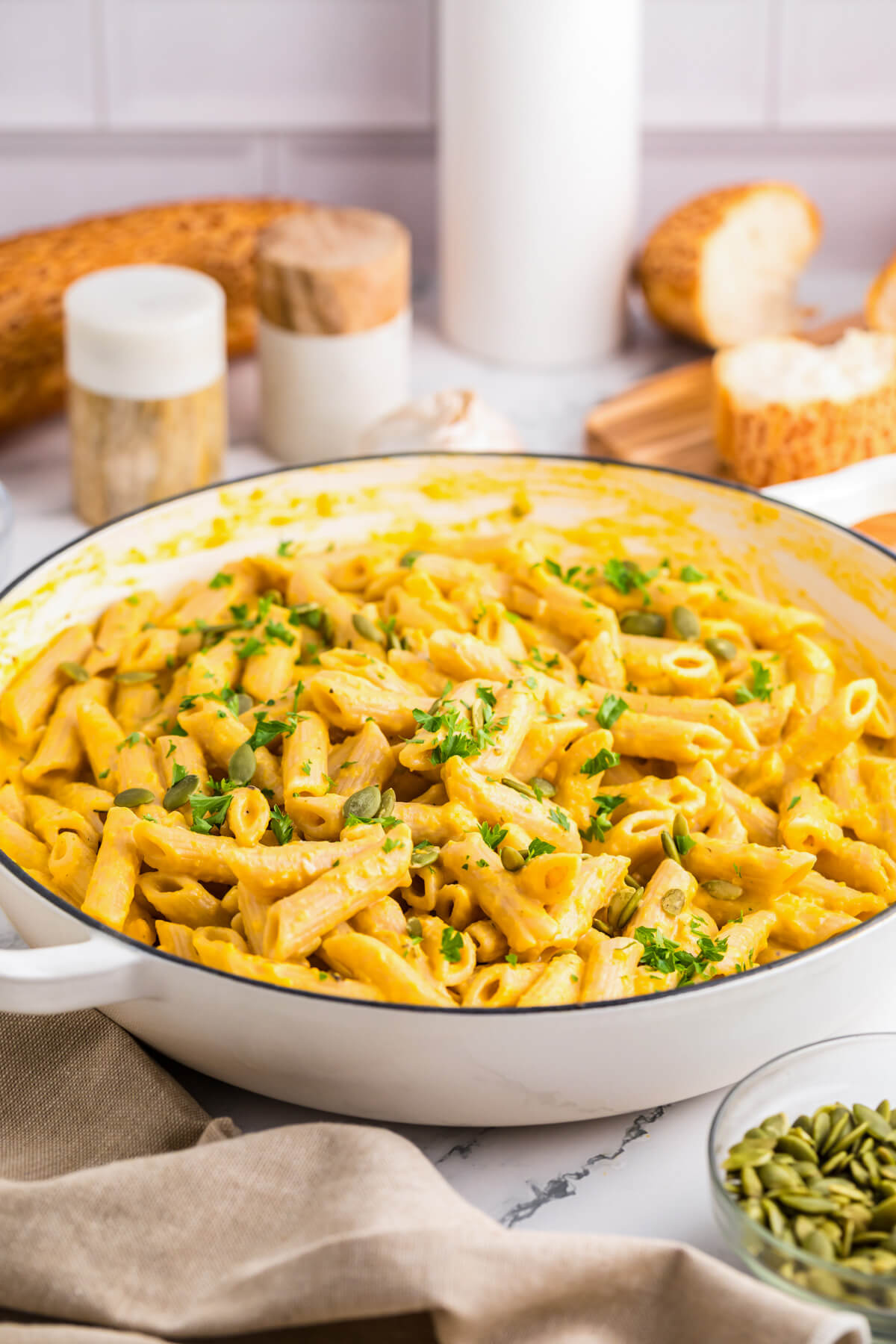 A white enameled pan filled with penne in a creamy pumpkin pasta sauce.