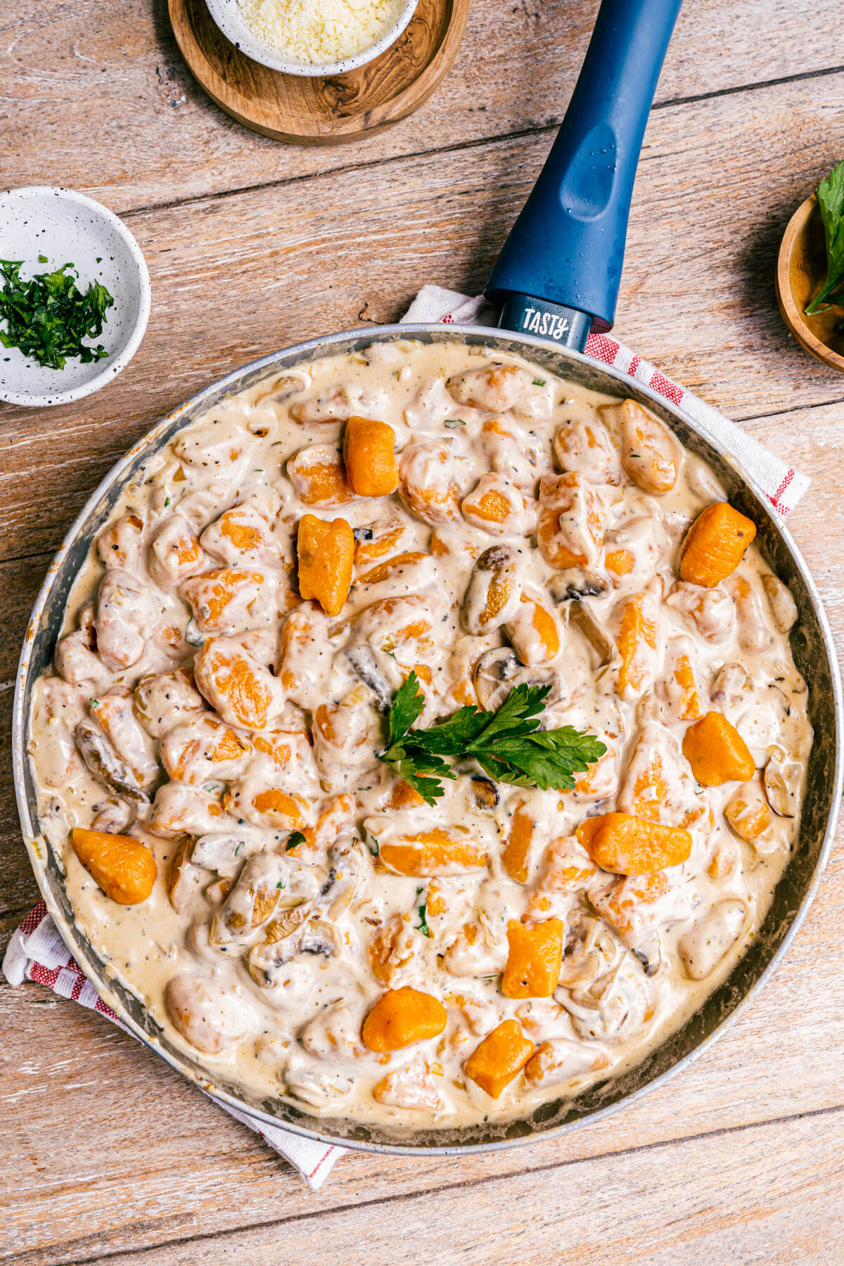 A pan full of vibrant orange sweet potato gnocchi swimming in a creamy mushroom sauce.