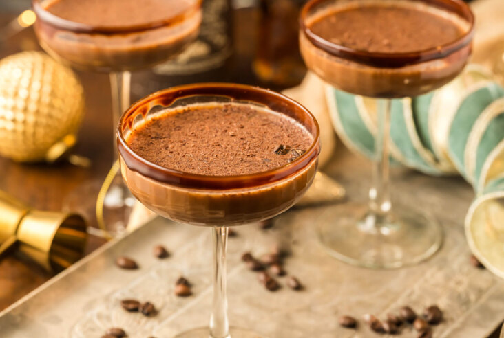 Three creamy brown Chocolate Espresso Martinis in coupe cocktail glasses garnished with chocolate rim and chocolate shavings.