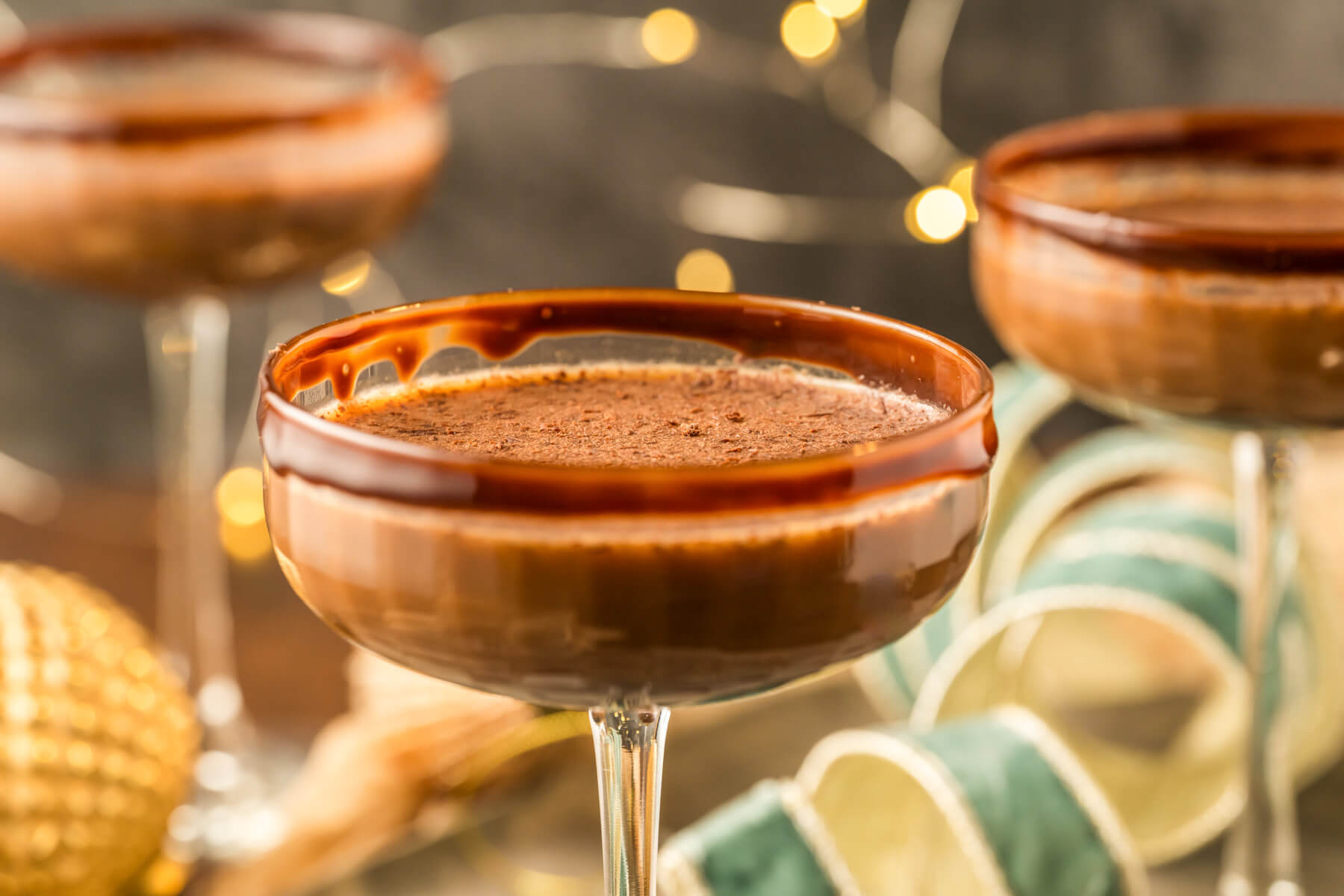 Three creamy brown Chocolate Espresso Martinis in coupe cocktail glasses garnished with chocolate rim and chocolate shavings.