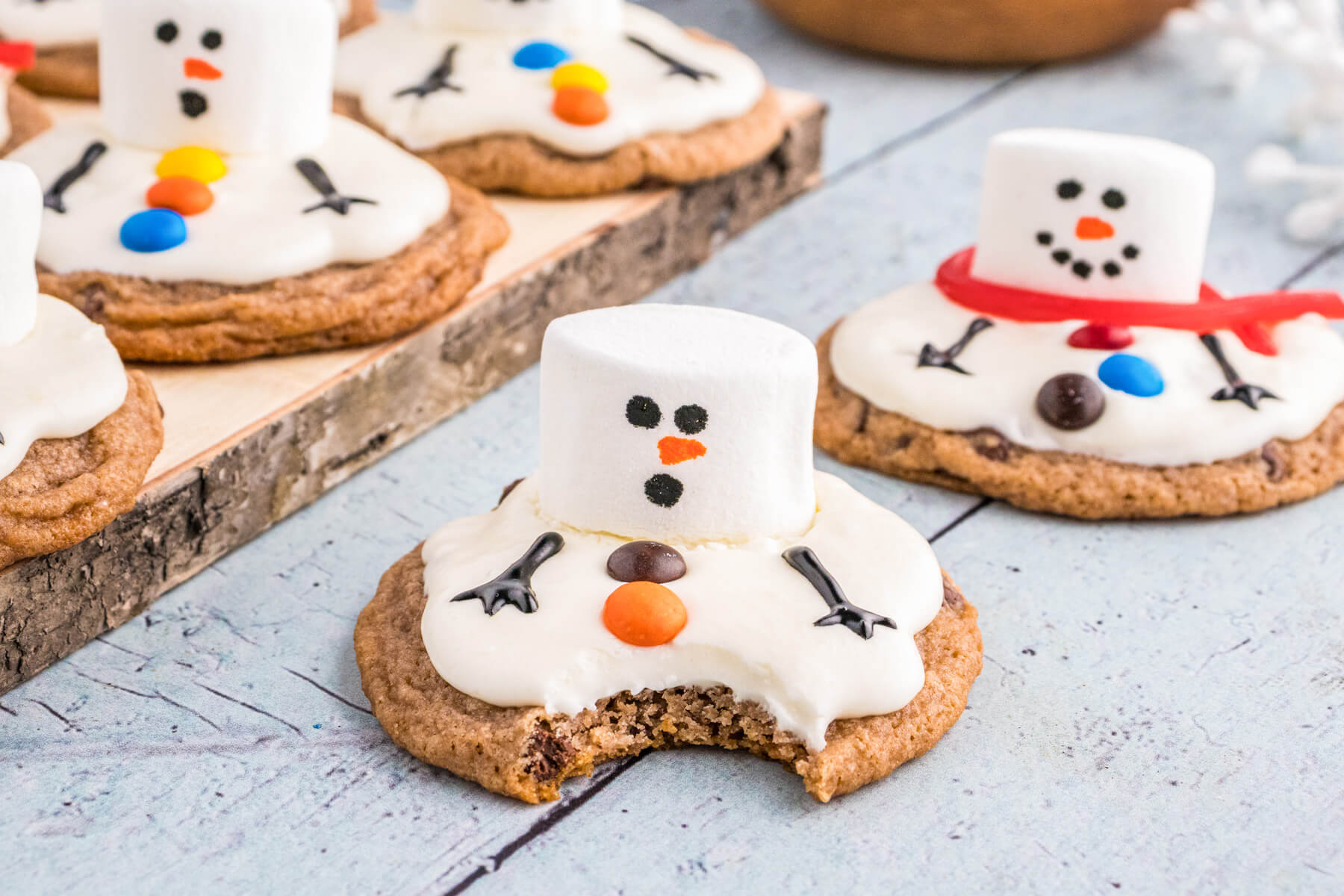 A Melted Snowman cookie decorate with a surprised face with a bite taken out.