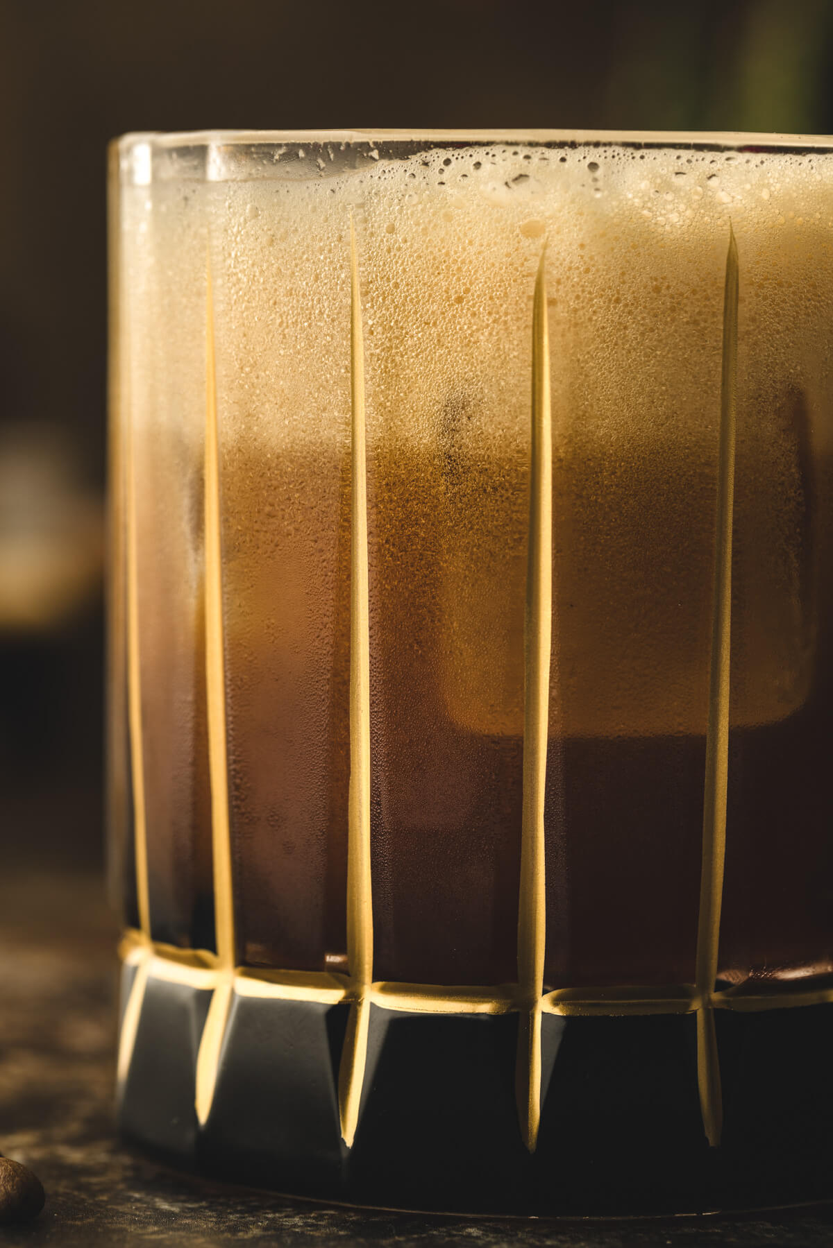 Close up of a Carajillo cocktail showing a distinctive top layer of coffee foam. 