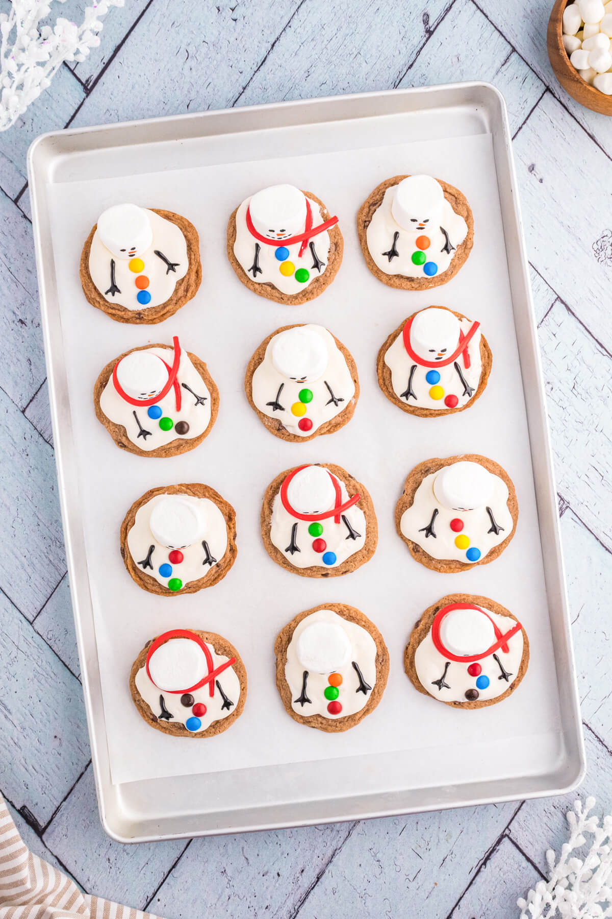 Fully decorated Melted Snowman Cookies on a parchment lined baking sheet. 