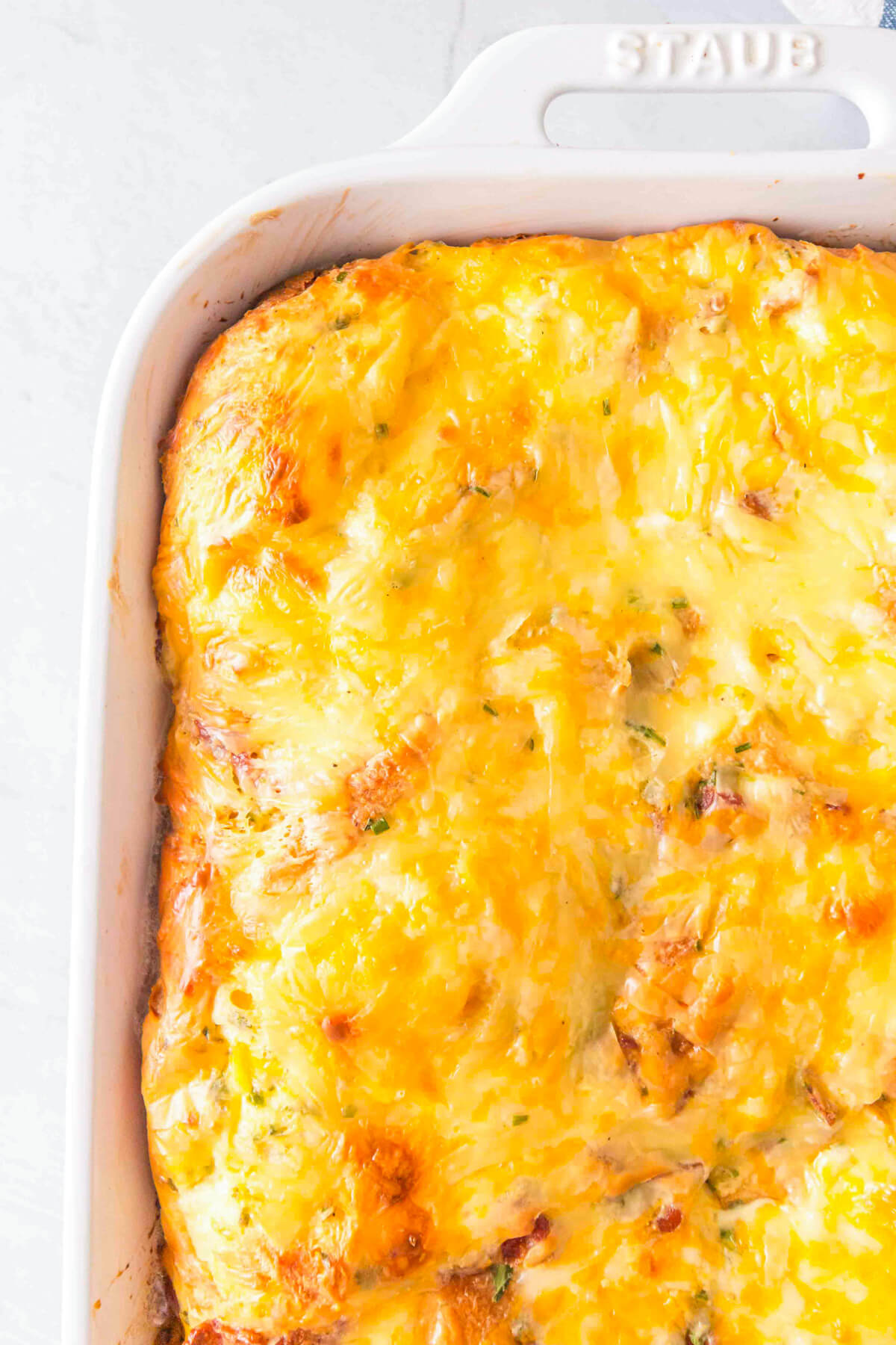 A 9 x 13 white baking dish filled with cheesy golden breakfast casserole.