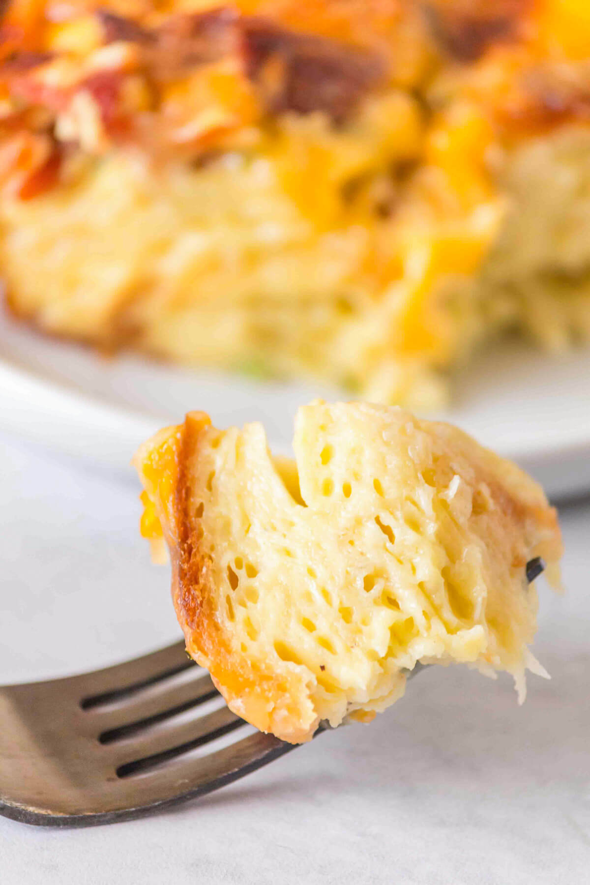 A fork holds a piece of egg coated croissant showing the light and airy casserole texture.