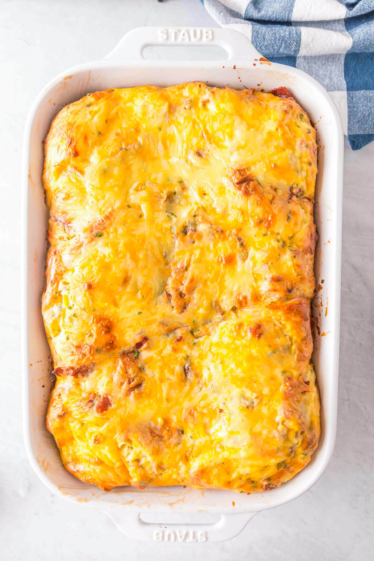A 9 x 13 white baking dish filled with cheesy golden breakfast casserole.