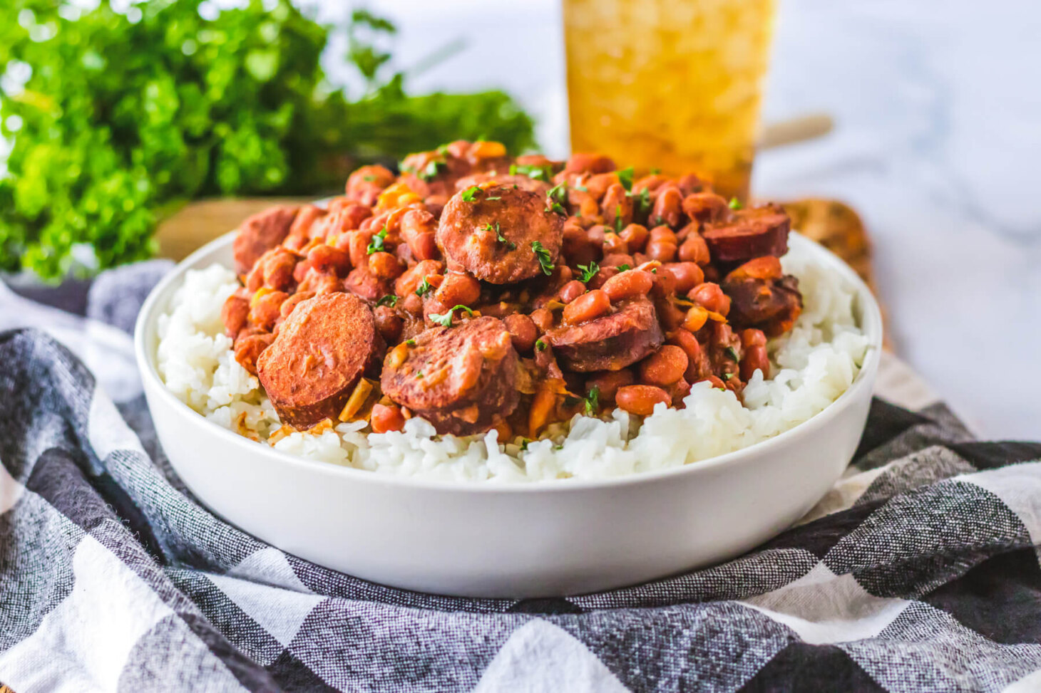A plate full of hearty and saucy red beans and rice with rounds of andouille sausage.