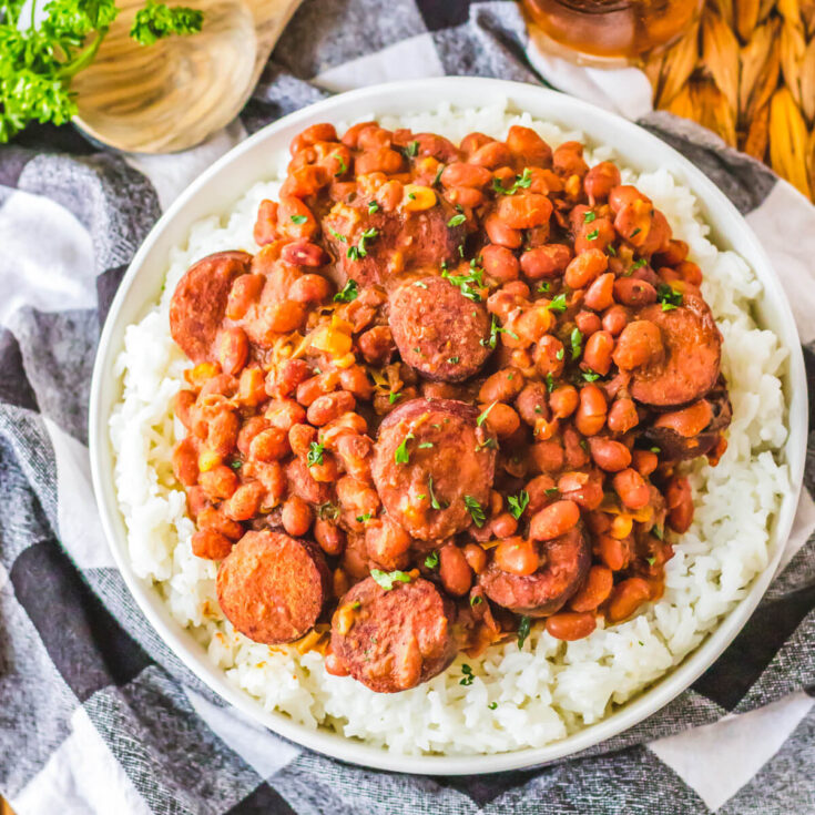 A plate full of hearty and saucy red beans and rice with rounds of andouille sausage.