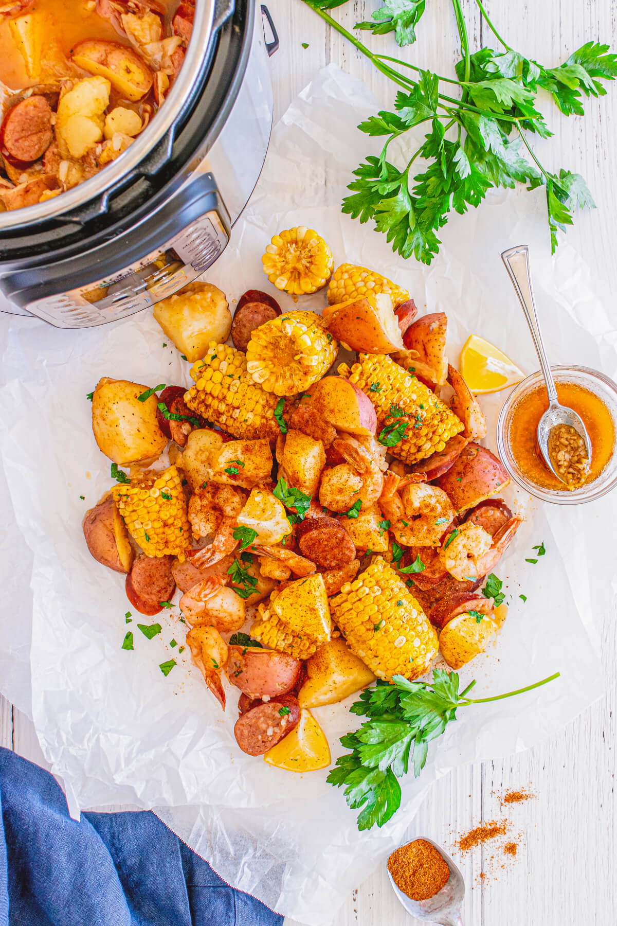 Cooked shrimp boil with spice coated shrimp, potatoes, sausage, and corn spread out on a white parchment paper.