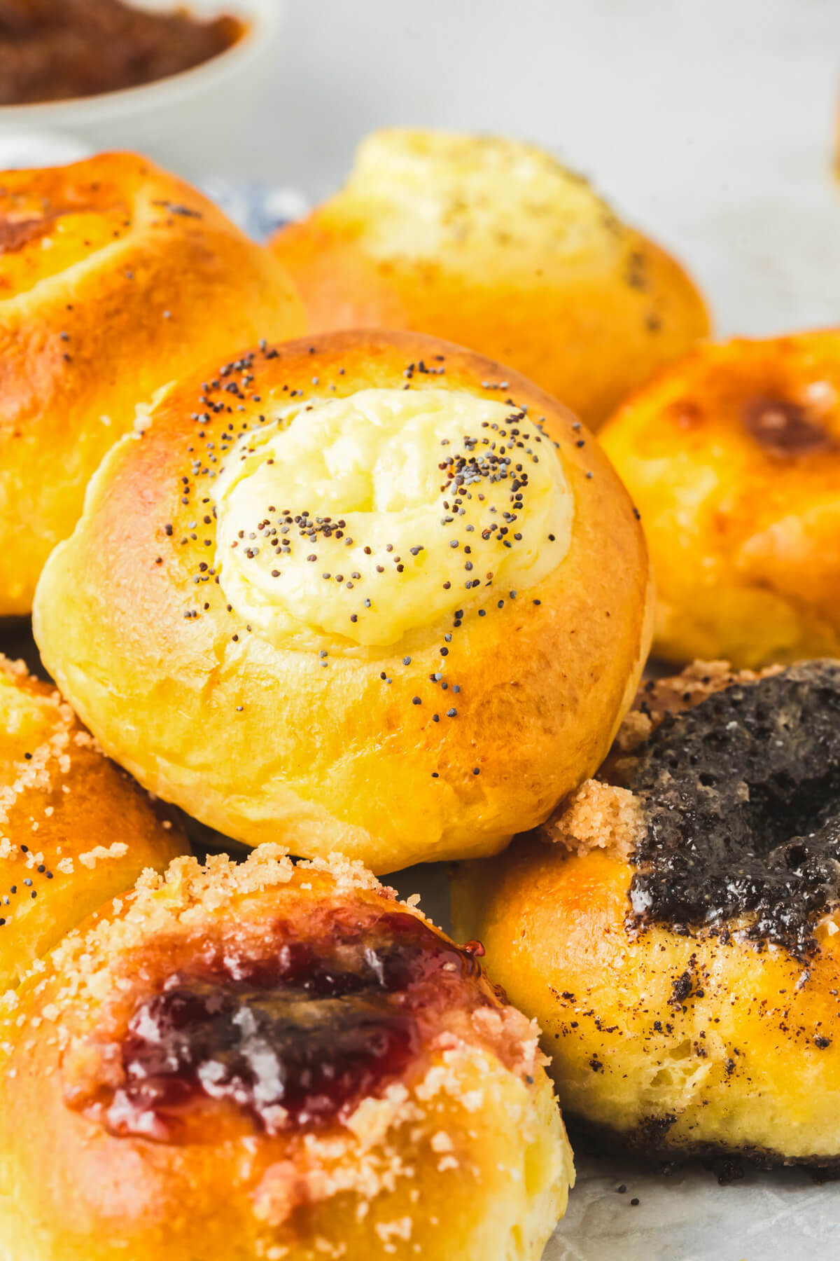 A plate full of golden baked kolaches filled with a variety of fillings.