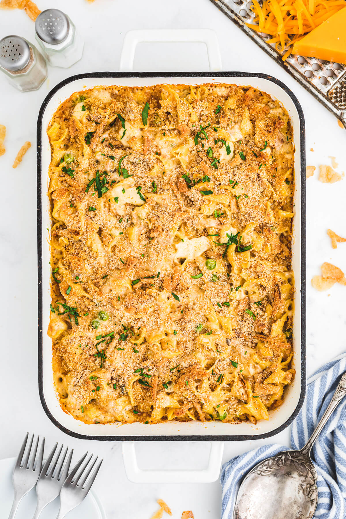 A white enamel baking pan full of golden baked, crumb topped Tuna Noodle Casserole.
