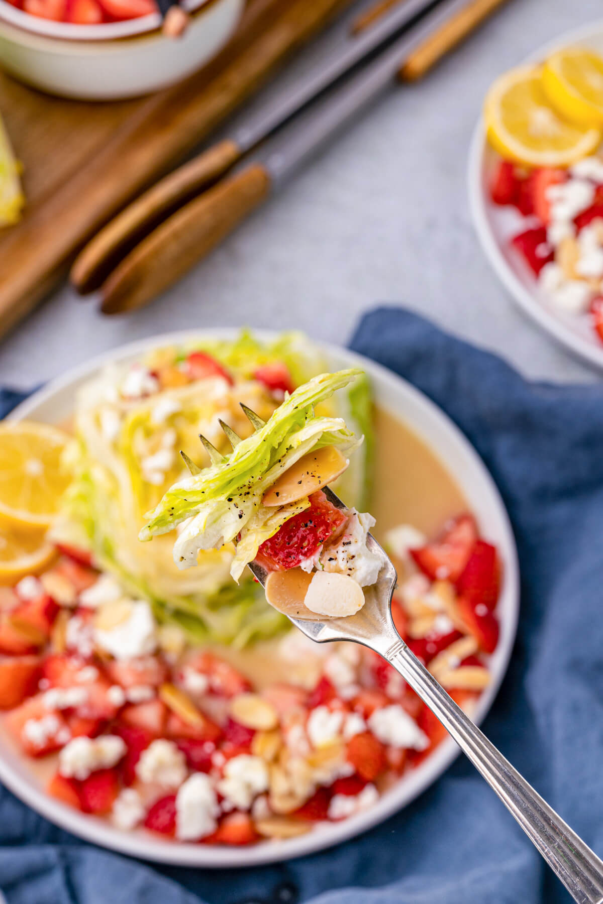 A fork holds a bite of strawberry feta wedge salad.