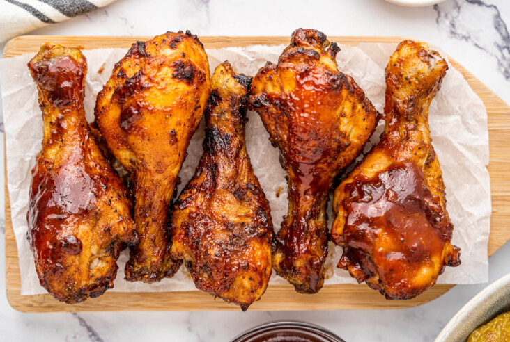 Crispy cooked chicken drumsticks coated in barbecue sauce on a platter.