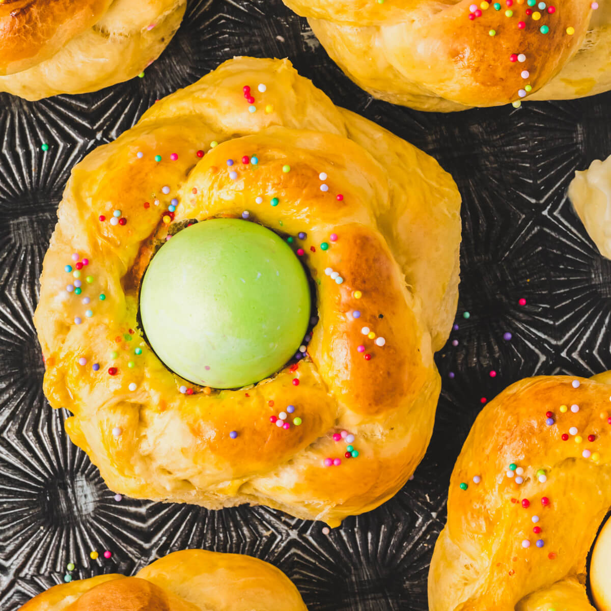 One golden baked Italian Easter Bread filled with a bright green coloured Easter egg on a baking sheet.