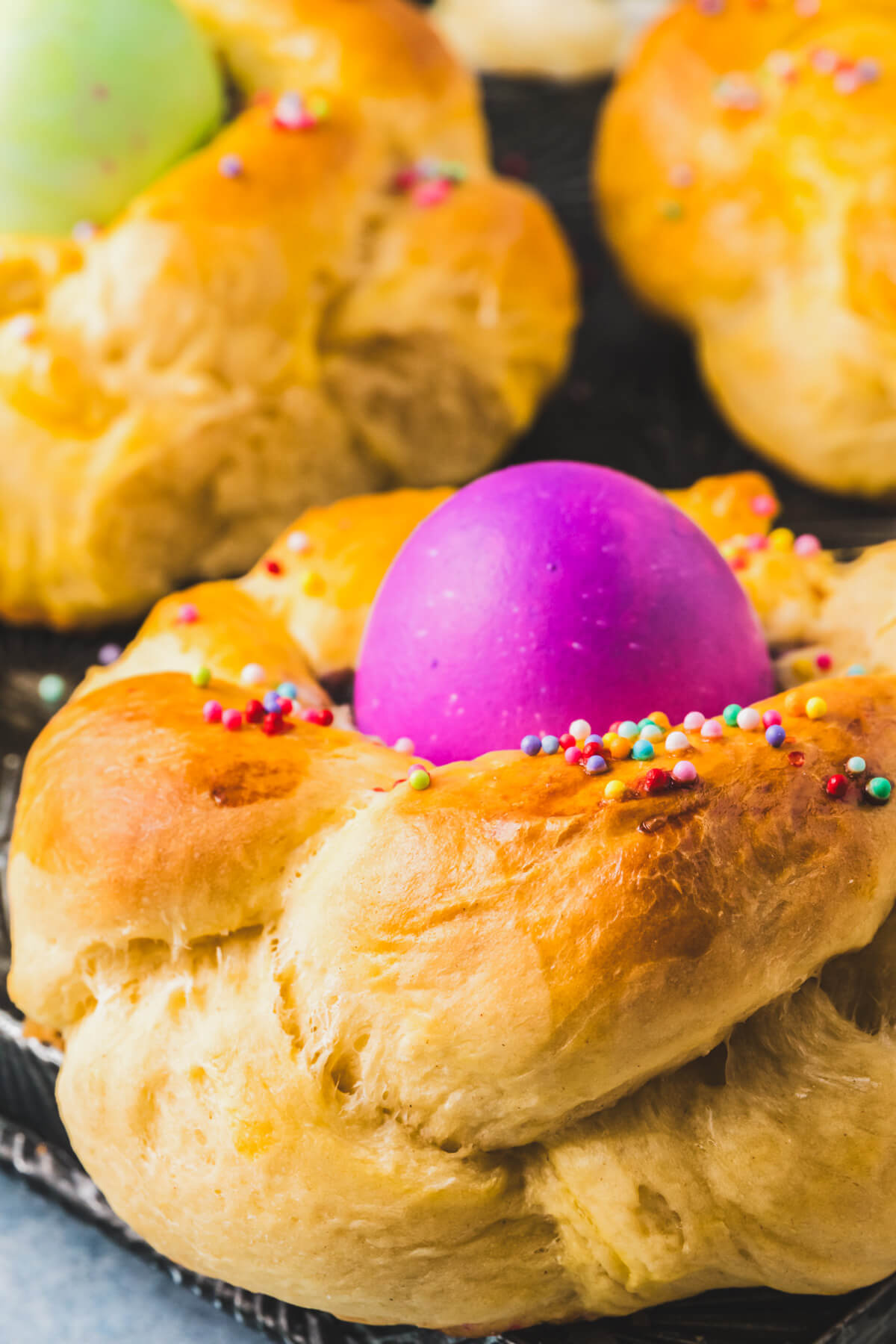 One golden baked Italian Easter Bread filled with a bright purple coloured Easter egg on a baking sheet.