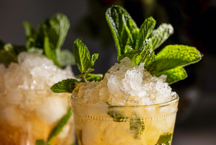Close up photo of shaved mounded ice in two mint julep cocktail glasses garnished with mint.