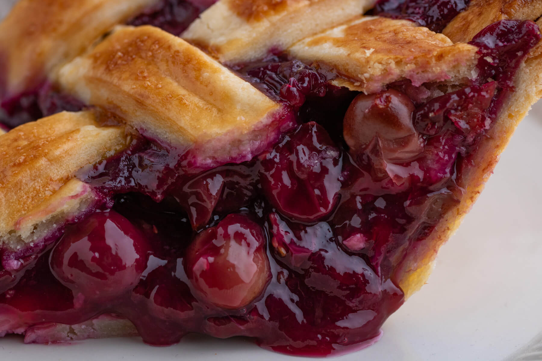 Close up of a slice of coronation grape pie with a golden baked lattice pie crust.