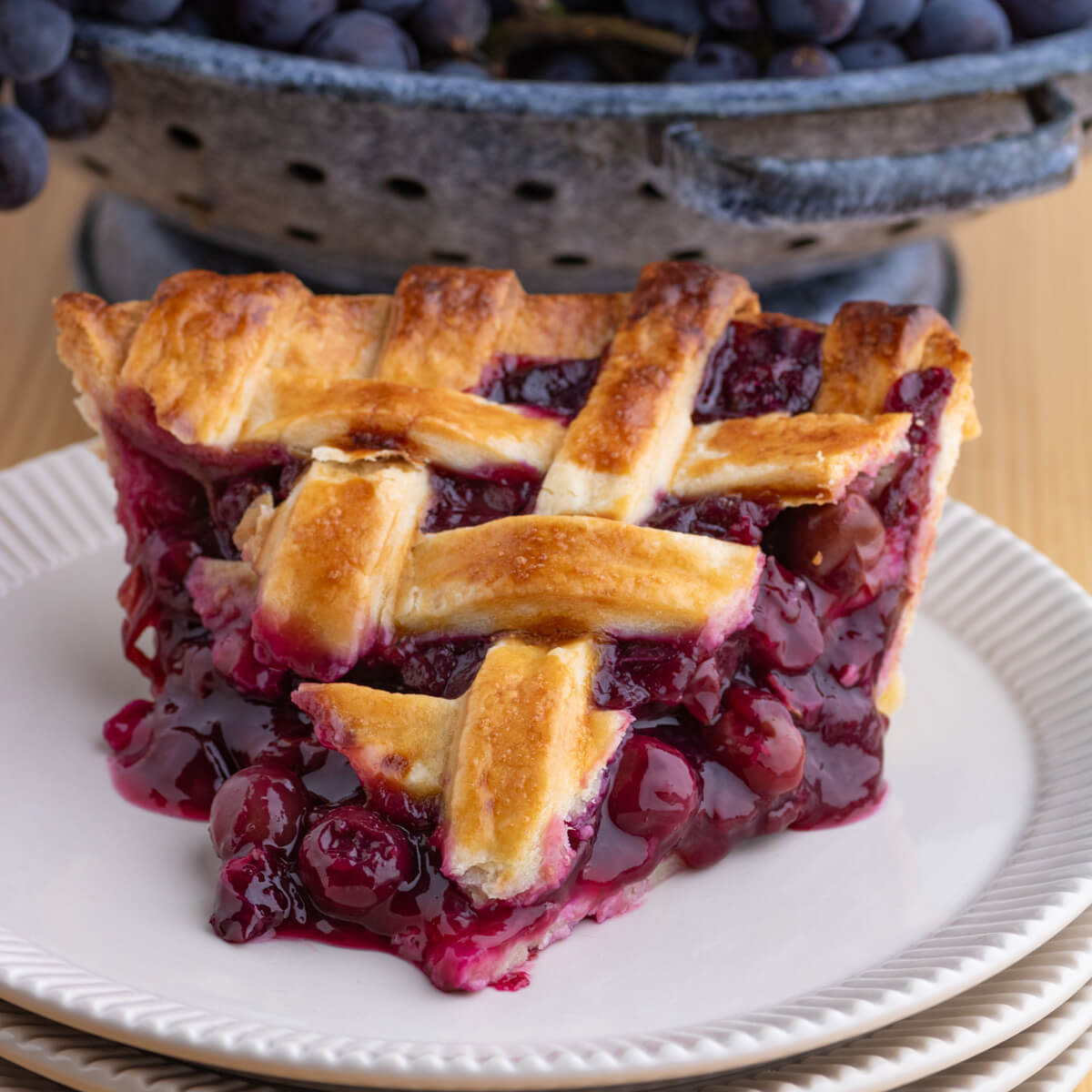 A slice of Grape Pie with a buttery golden baked lattice pastry design.