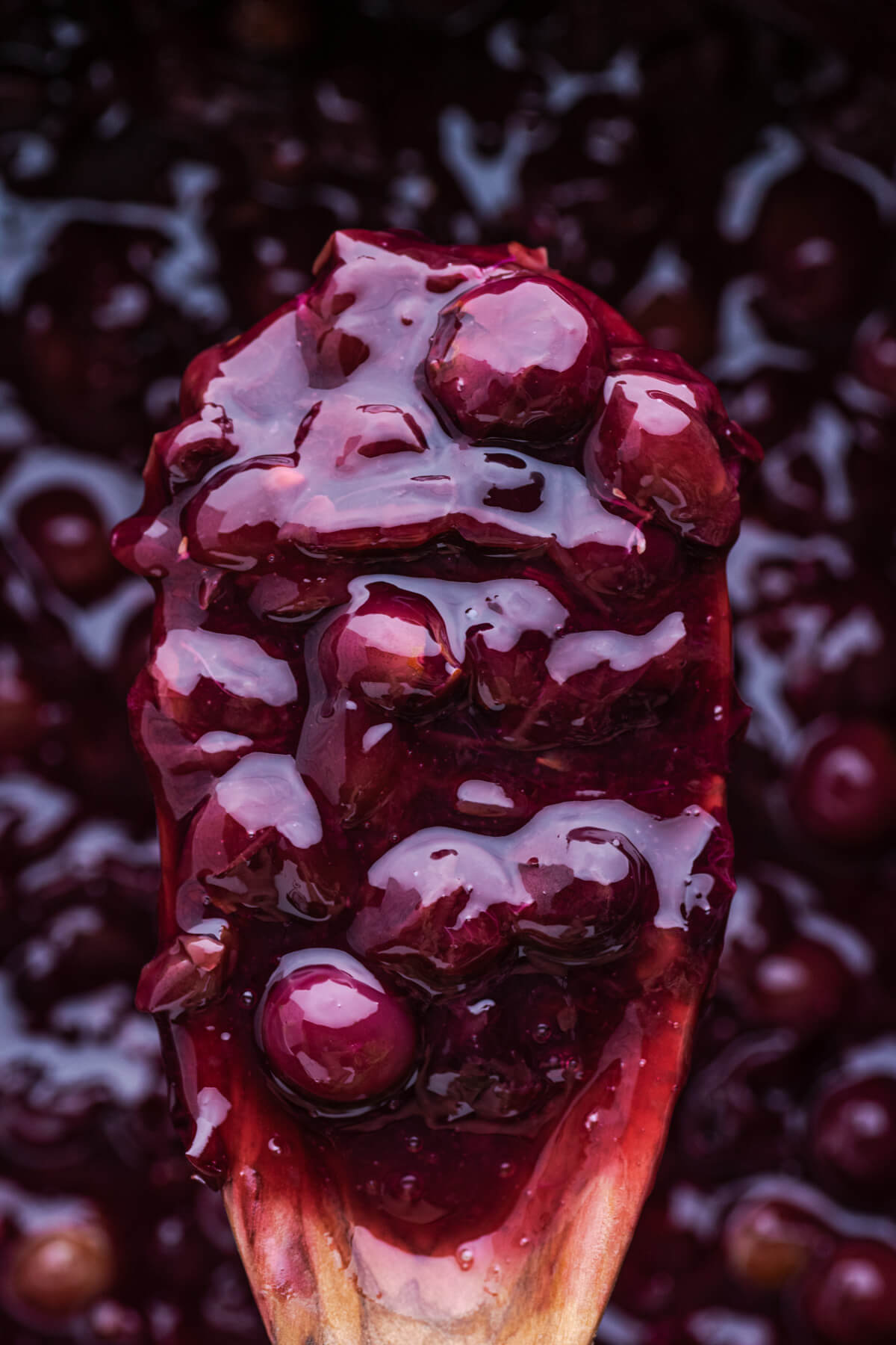 A wooden spoon filling with grape pie filling.