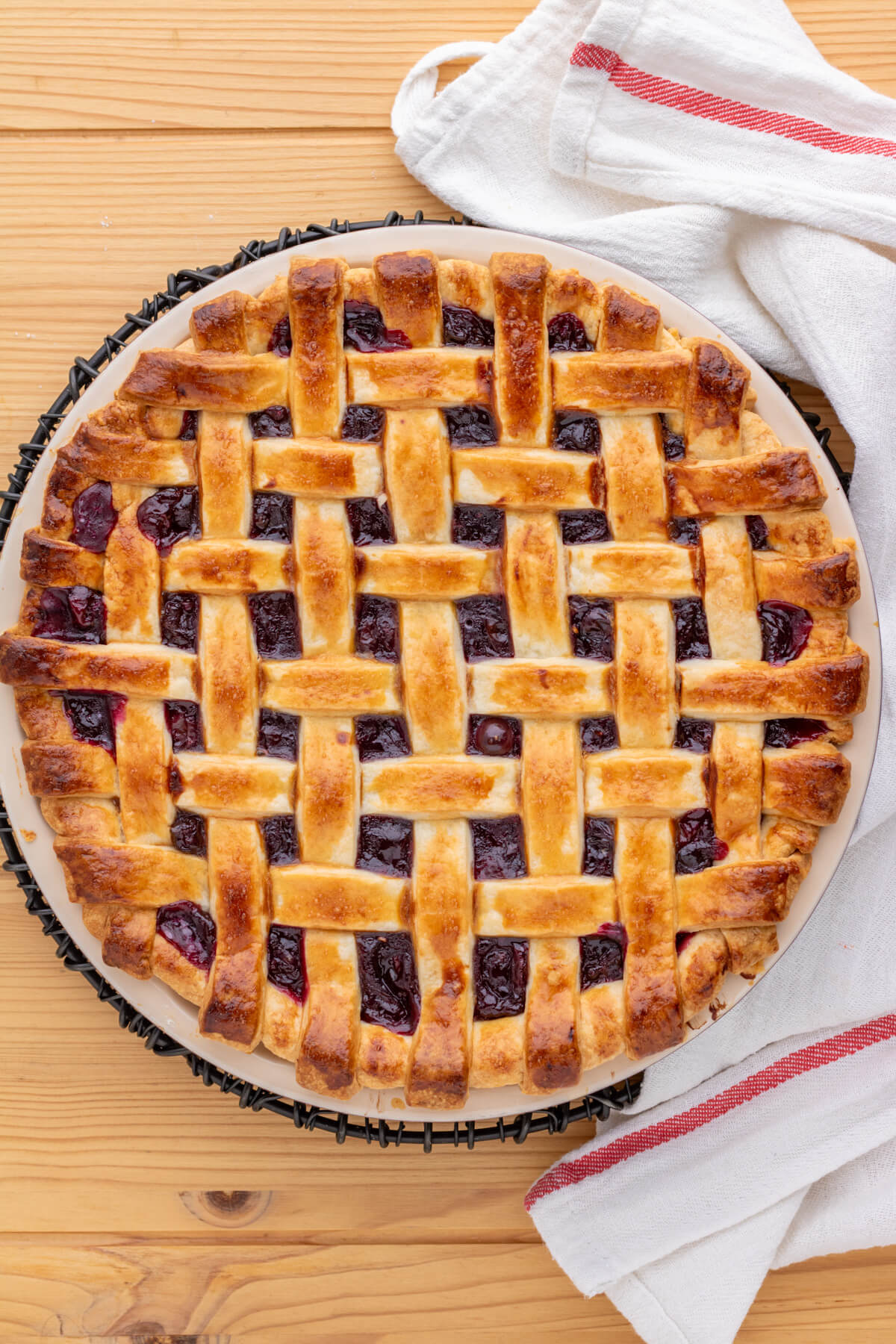 A golden baked fruit pie with a perfect lattice crust on a wooden table.