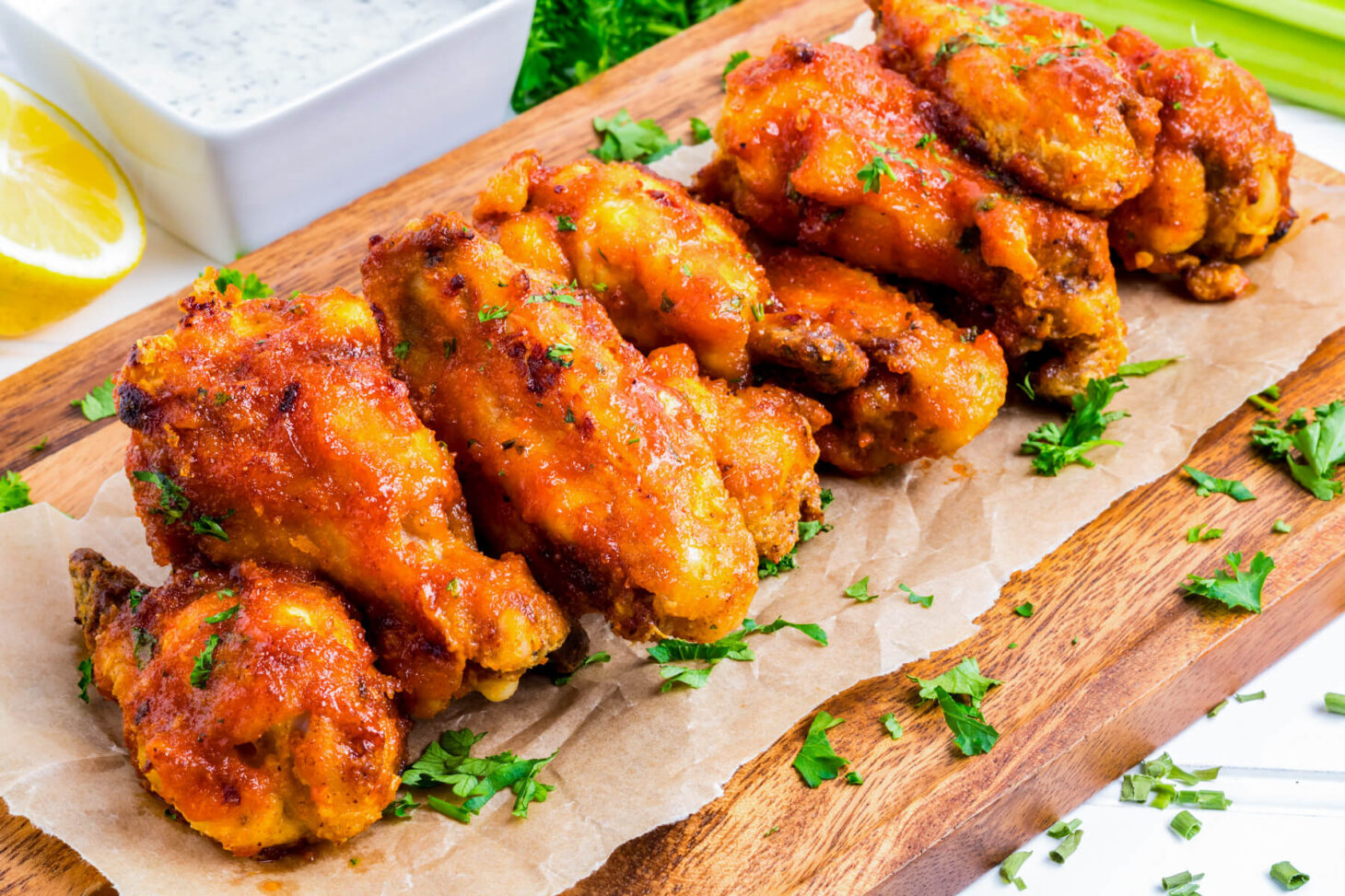 Vibrant orange Hot Honey Chicken Wings stacked on a wooden platter.