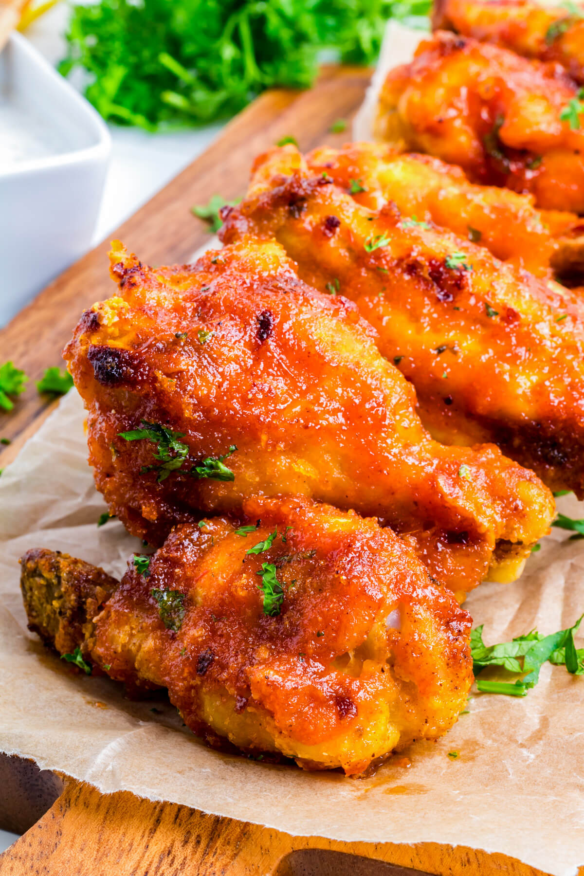 Vibrant orange Hot Honey Chicken Wings stacked on a wooden platter.