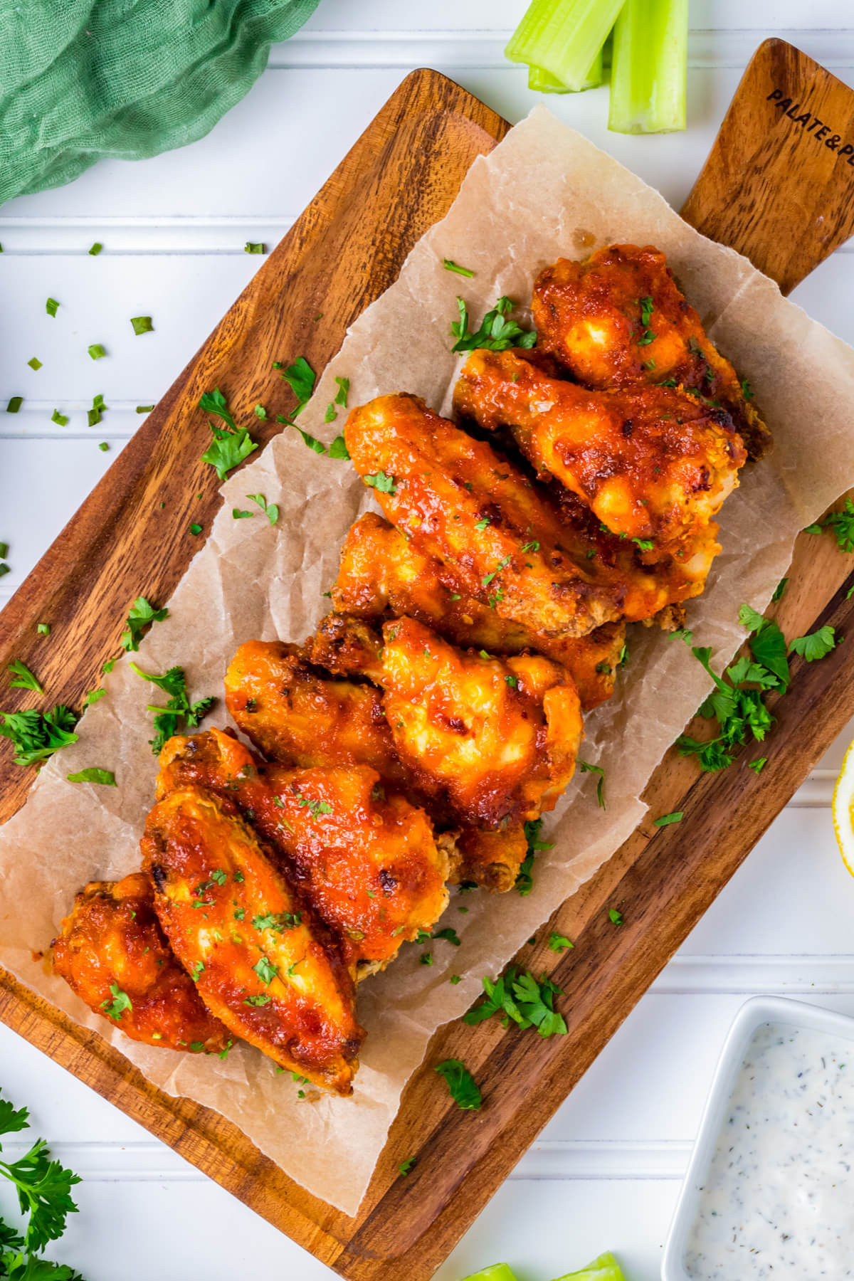 Vibrant orange Hot Honey Chicken Wings stacked on a wooden platter.