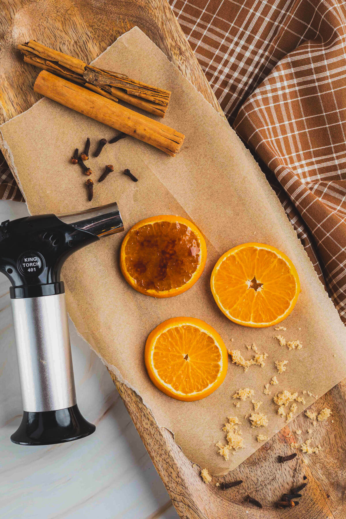 A small kitchen torch beside bruleed and non bruleed orange slices.